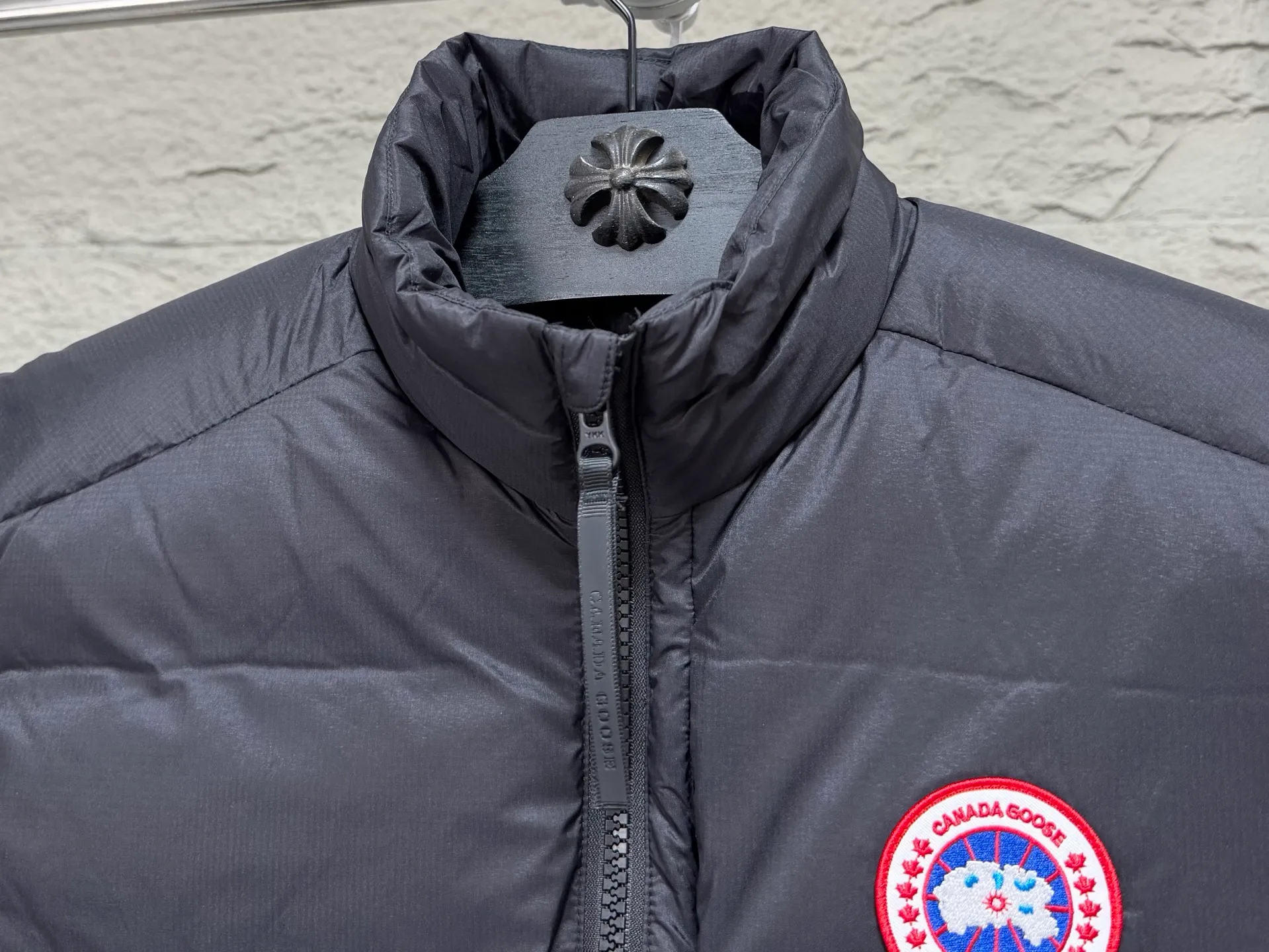 (High-quality) Canada Goose/Big Goose stand-collar lightweight down vest ●Selected tear-proof textured fabric, fine plaid texture, wind-resistant and durable, taking into account both light weight and toughness. ●Horizontal quilting segmented down lock technology, the down is evenly filled, not easy to run away, fluffy and not bloated. ●Classic red and black round emblem embroidery, the brand logo is exquisite and three-dimensional, low-key and high-end. ●High stand-up collar and windproof design, YKK zippers are smooth and durable, and the drawstring at the hem can be tightened freely to lock in warmth. ●Practical pockets on both sides make it easy to store small items; the stowable and portable design does not take up space when traveling. ●The cut is loose and neat, not flattering to your body shape. It can be worn alone in spring and autumn or layered with a coat in winter. It is suitable for urban commuting and outdoor travel. COLOUR:Black red label SIZE: S M L XL XXL